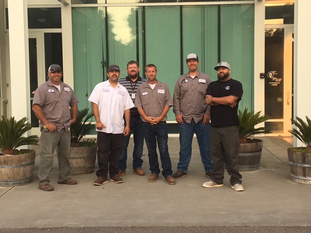 Six facilities employees pose outside the FPS building
